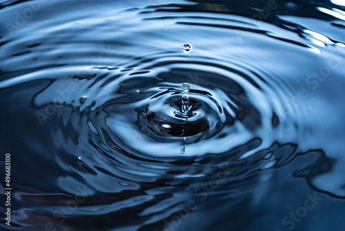 Drops and ripples. Close-up of blue water rings, circular reflections, waves on the liquid surface.