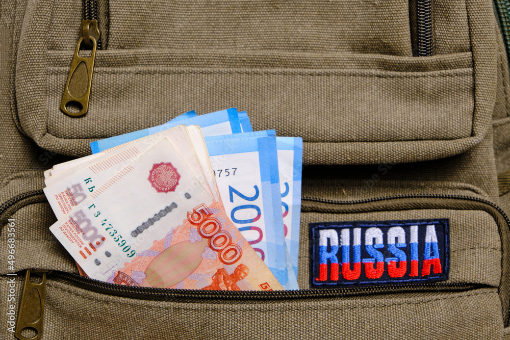 Obraz premium Paper banknotes Russian ruble in denominations two and five thousand pocket backpack with inscription Russia.