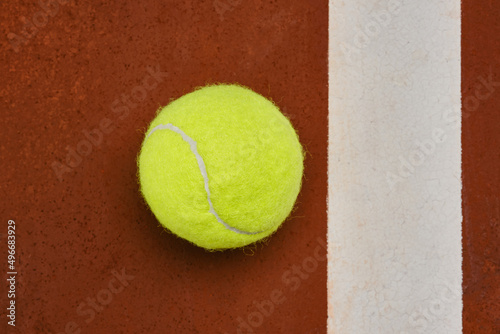 Tennis ball on a orange court surface with white stripe. Shallow depth of field © VLADISLAV