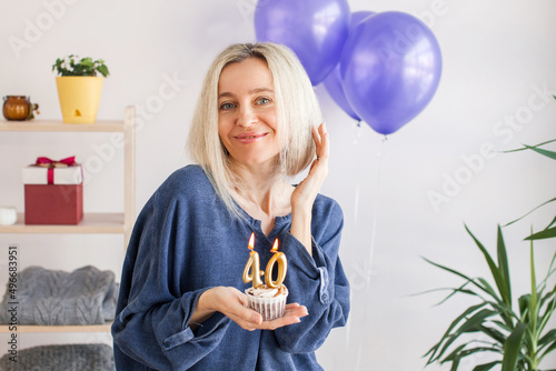 Photography Portrait of happy middle aged woman holding birthday cake with lit candles