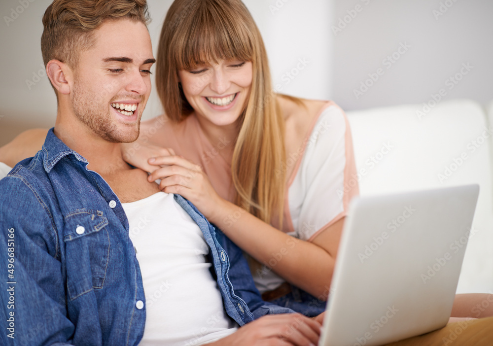 Using their laptop from the comfort of the couch. A young couple using a laptop while relaxing on the couch. Using their laptop from the comfort of the couch. A young couple using a laptop while relaxing on the couch.