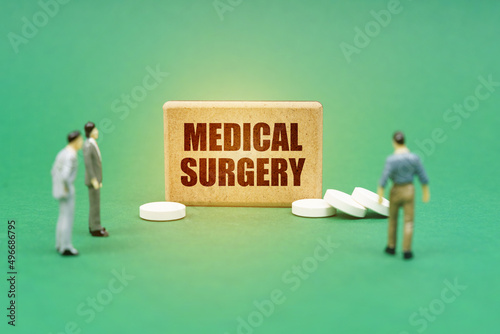 On the green surface are pills, miniature figures of people and a sign with the inscription - MEDICAL SURGERY photo