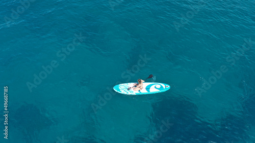 Aerial drone photo of fit unidentified woman paddling on a SUP board or Stand Up Paddle board in deep blue sea © aerial-drone