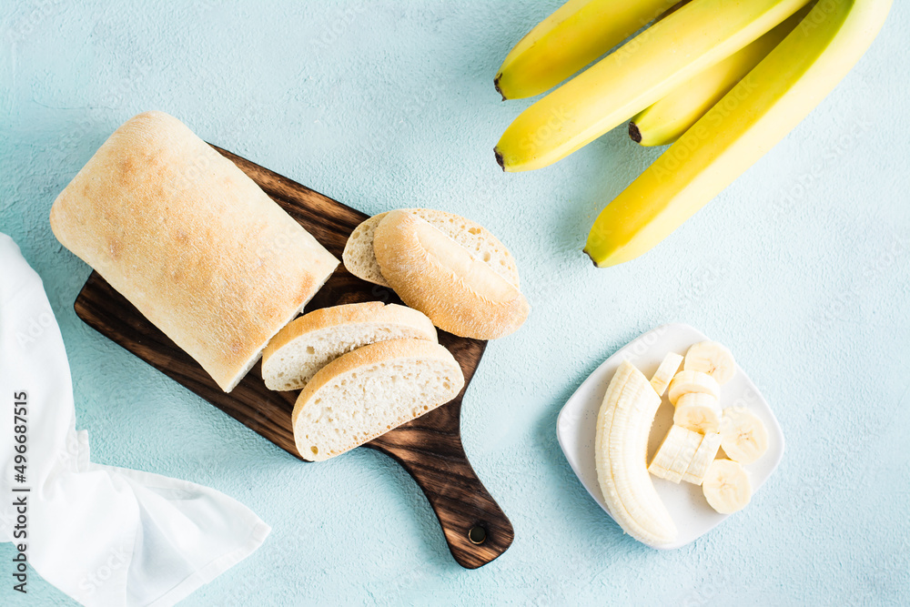 Fototapeta premium Fresh sliced banana bread and bananas on a plate on the table. Homemade baking. Top view
