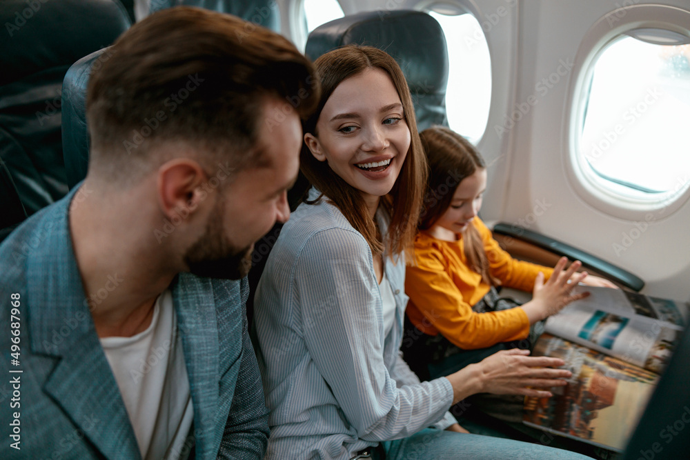 Cheerful parents traveling with daughter on airplane