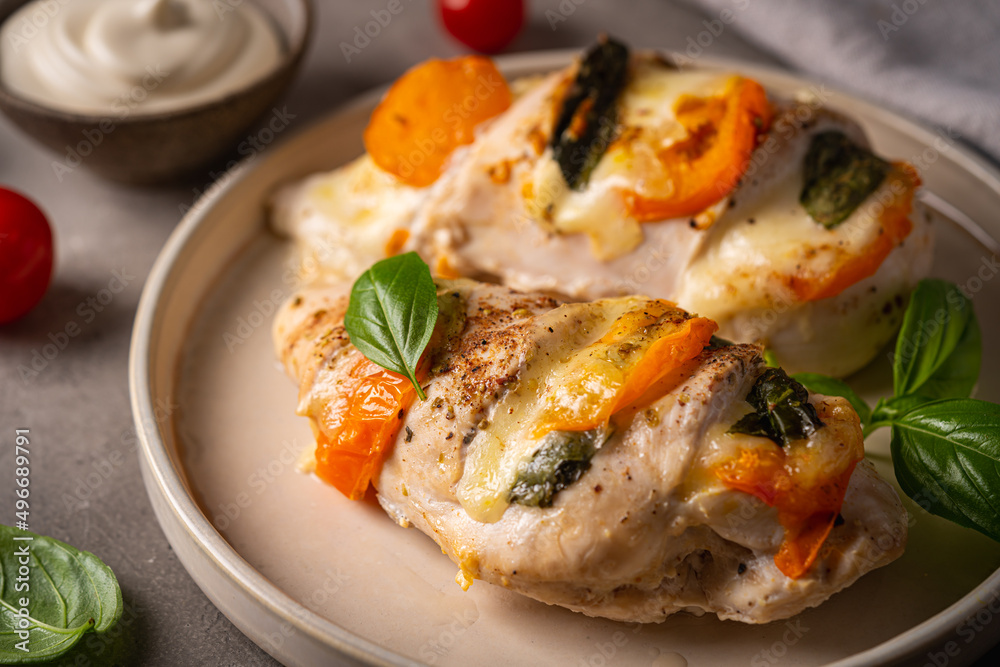 Baked Tomato, mozzarella and basil stuffed chicken breasts on gray table
