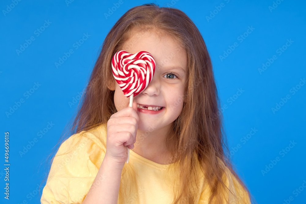 Toothless child. Cute little girl smiles broadly with lollipop  in hands. The first milk tooth fell out. Carefree childhood concept and dental hygiene