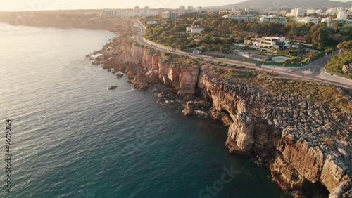 Aerial view of the rocky coast by the sea in Cascais town at sunset, Portugal