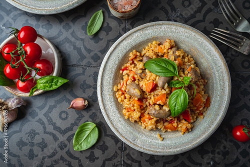 bulgur with chicken hearts and vegetables. Delicious healthy dish on dark background, top view. Bulgur pilaf