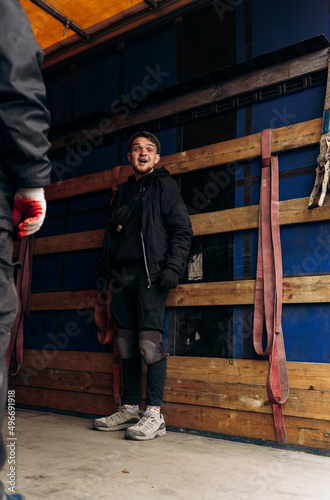 A man in torn knee pads smiles in surprise in a truck trailer truck humanitarian aid war in ukraine

