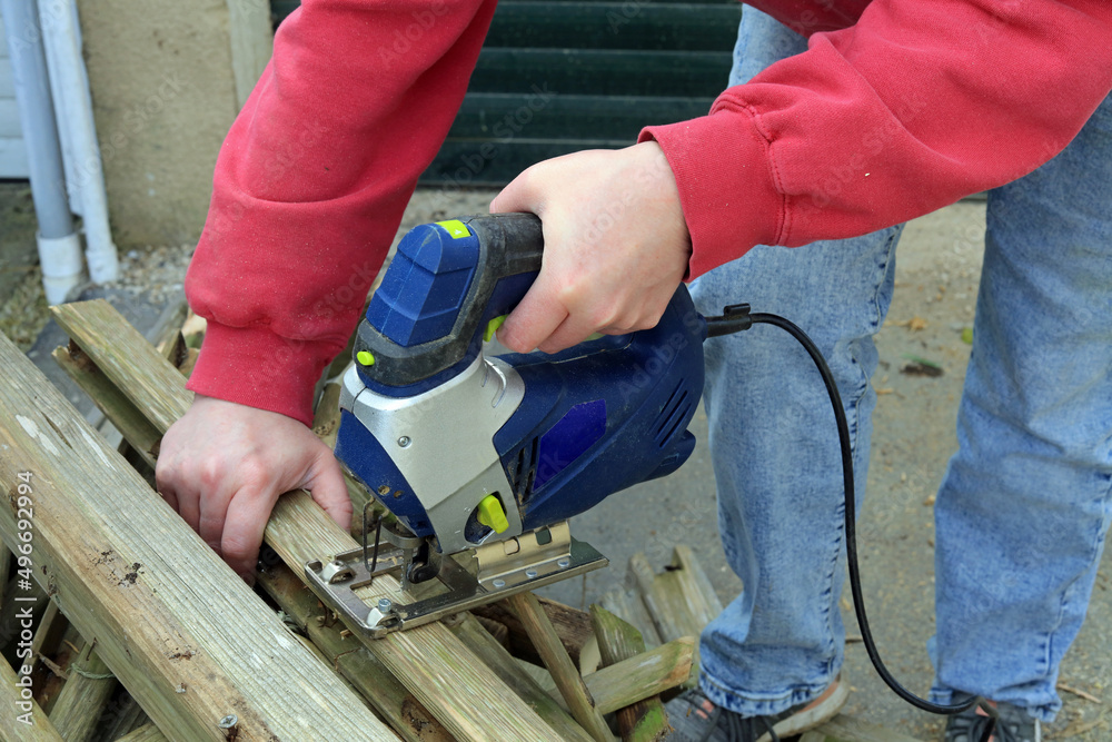 an electric jigsaw being used to cut timber. an electric jigsaw being used to cut timber.