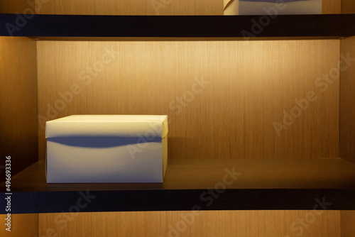 White cardboard box on a shelf in a wooden cabinet.