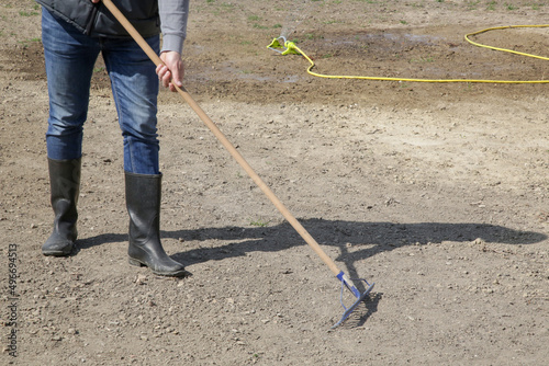 Farmer using a rake to create a fine top layer of soil. Planting grass. Process of sowing and growing a lawn. Serie of photos.