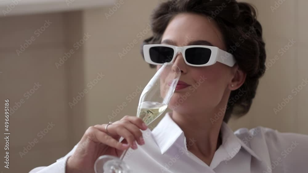 Beautiful brunette with a glass of champagne in slow motion. Attractive woman with wavy hair enjoying sparkling golden drink with blurred background. Holiday concept
Beautiful brunette with a glass of champagne in slow motion. Attractive woman with wavy hair enjoying sparkling golden drink with blurred background. Holiday concept