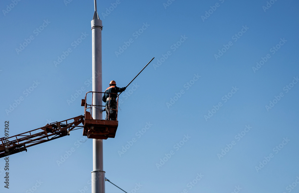 man paints a post in city