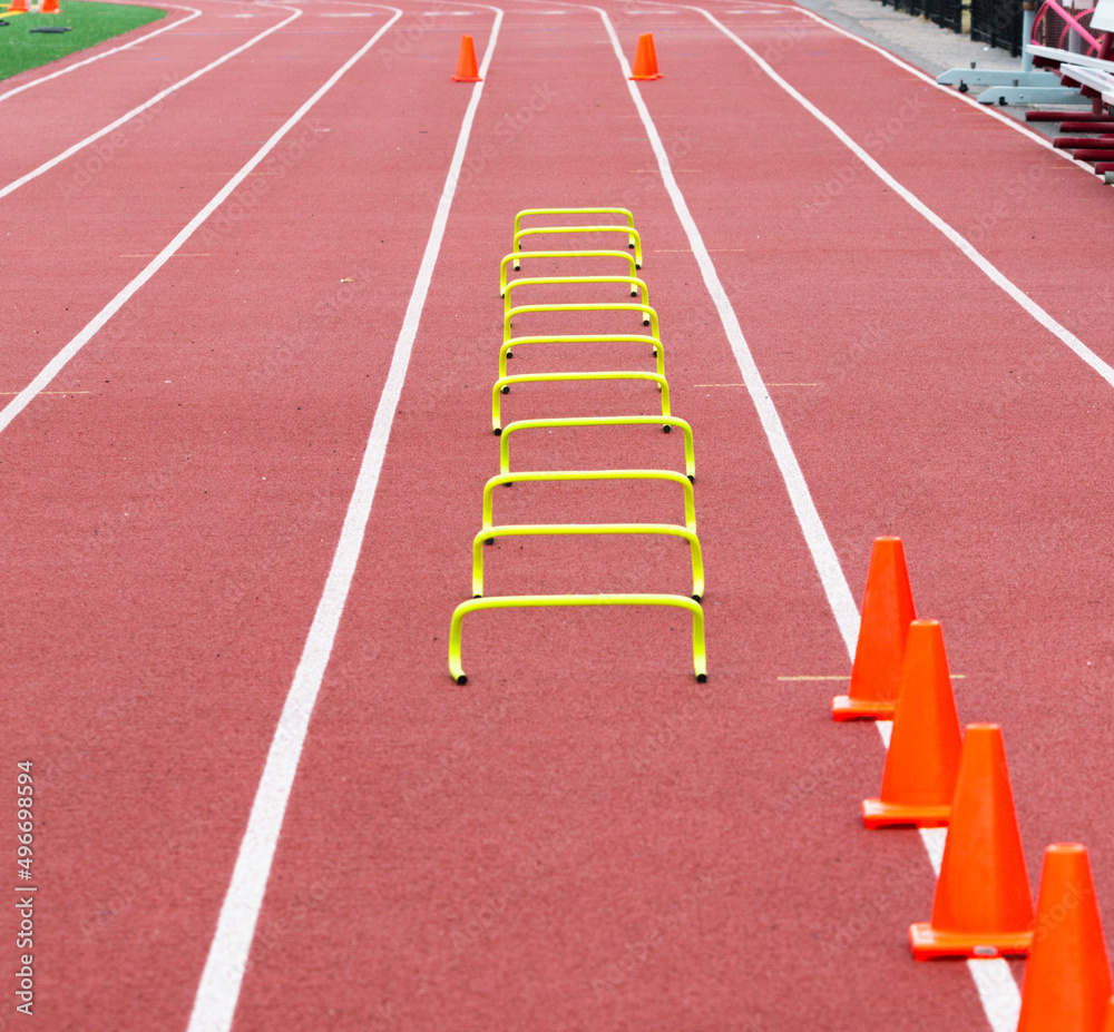 A row of small hurdles set up in lane on a track for runners to run over