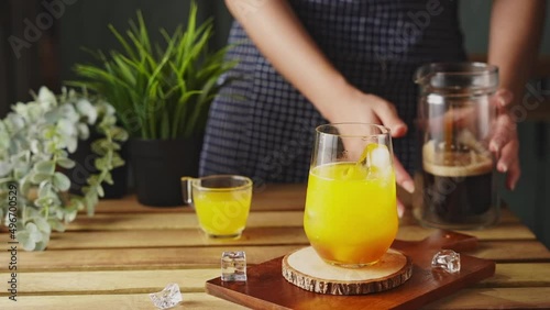 Iced black coffee With orange Juice. Cold coffee with tonic. The barista mixes ice cubes, tonic and cold coffee. 
