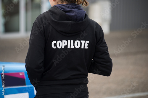 Closeup of girl wearing a black printed sweat shirt with text in french : copilote, traduction in english : copilot