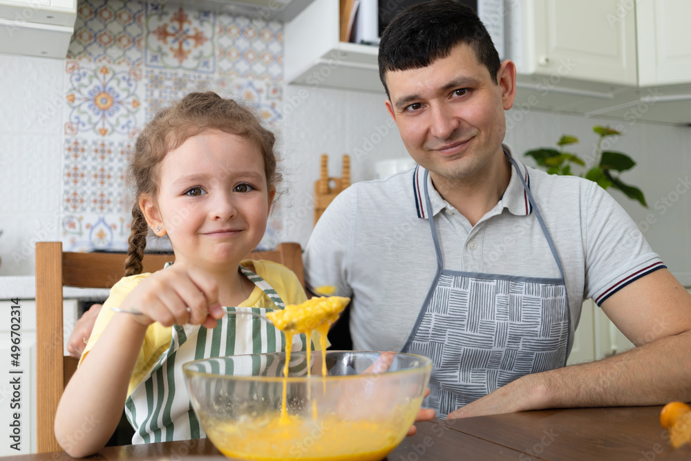happy daughter help to father in kitchen. kid cooking food with dad. little girl, man in apron in preparing dough. child baking pie, cookies, making biscuit. family together home happy daughter help to father in kitchen. kid cooking food with dad. little girl, man in apron in preparing dough. child baking pie, cookies, making biscuit. family together home