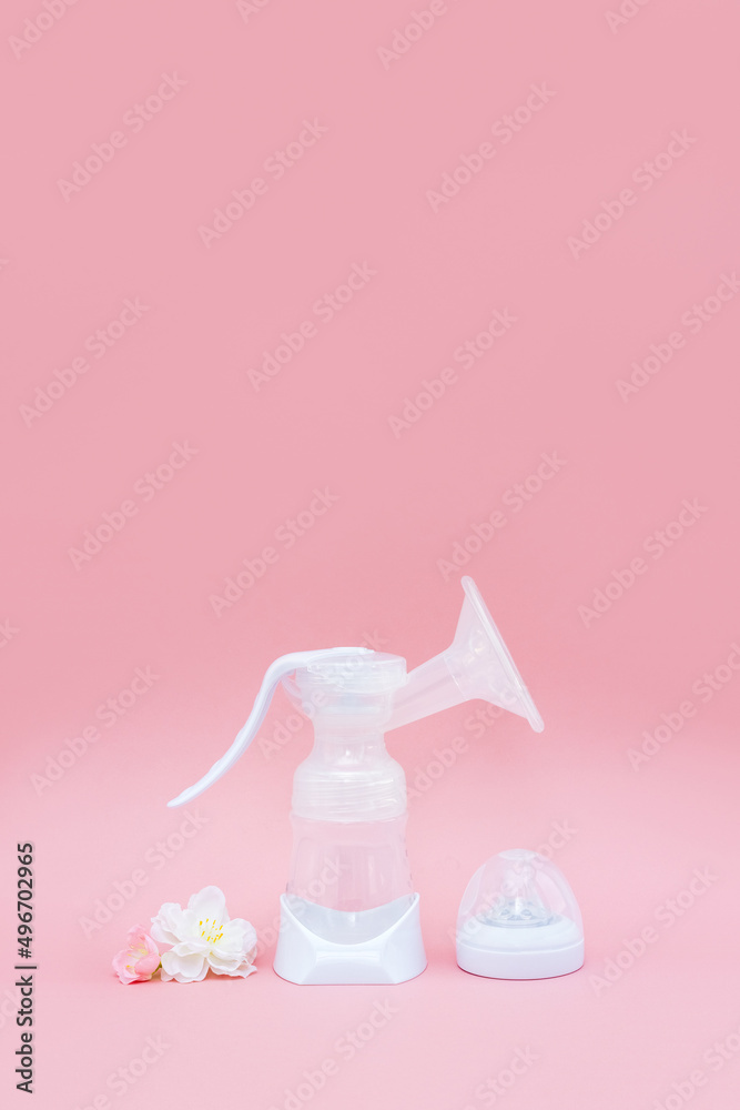 Breast pump and sakura flowers on pink background. Breastfeeding concept. Vertical banner, copy space