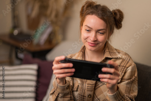 A cute girl plays on a portable game console. Close-up. Video games, mobile games, travel, entertainment on the road, transport, virtual reality, communication with friends.