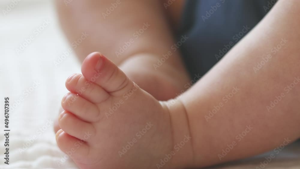 close-up bare feet and toes of infant baby legs in white sheet. newborn tiny fingers feet moving. caucasian little baby foot macro view. barefoot child legs close-up bare feet and toes of infant baby legs in white sheet. newborn tiny fingers feet moving. caucasian little baby foot macro view. barefoot child legs