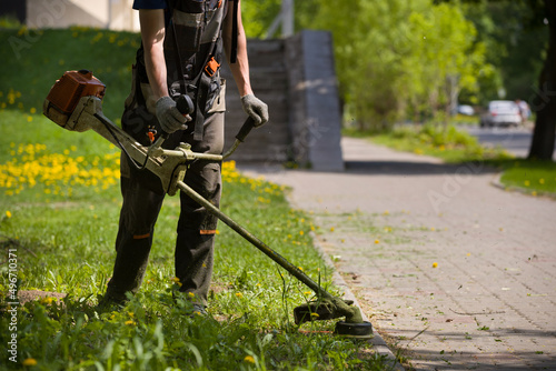 Foto A man mows the grass in a grassy field along a footpath on a warm sunny day