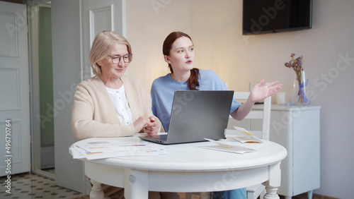 A social worker helps an old lady talk to her family using a laptop
