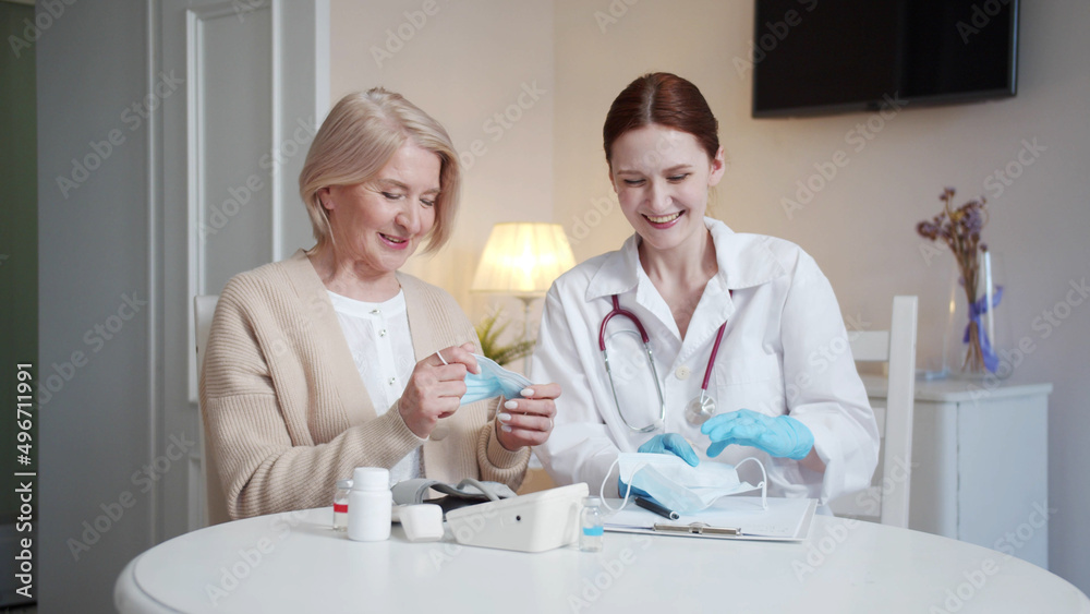 A doctor and an elderly woman take off medical masks together. They sigh in relief A doctor and an elderly woman take off medical masks together. They sigh in relief