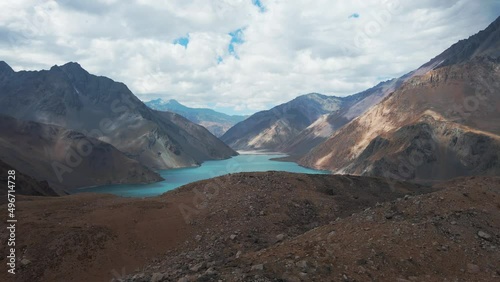 Aerial dolly in of El Yeso turquoise water dam enclosed between Andean mountains on a cloudy day, Cajon del Maipo, Chile photo