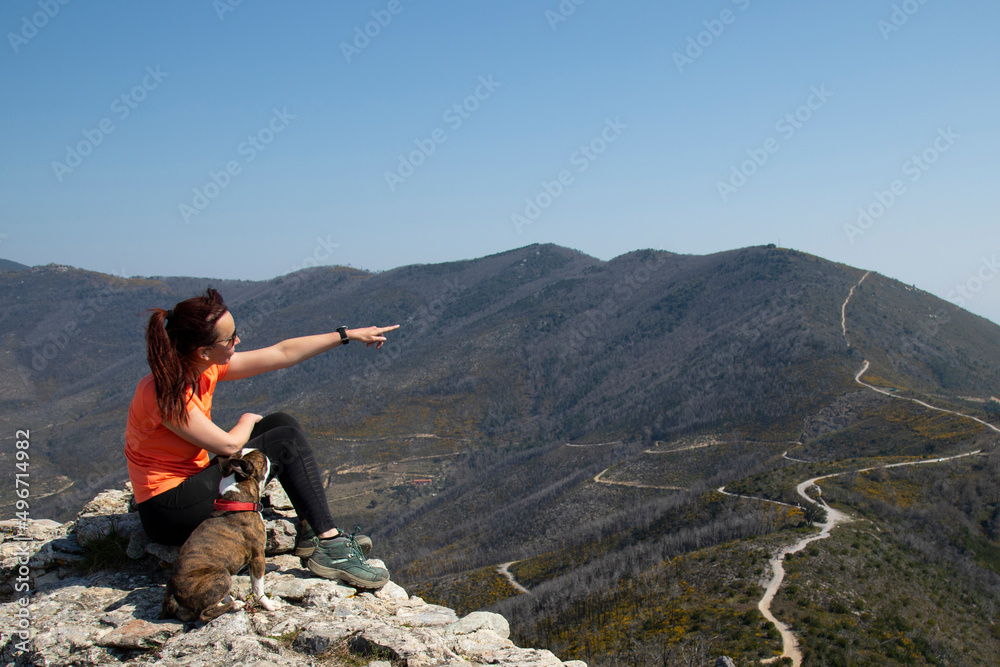 trekking woman with Boston terrier on  looks into the distance