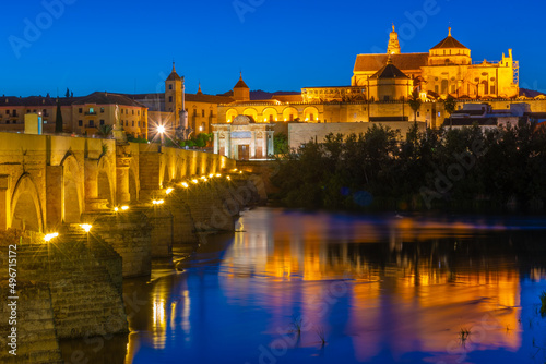 Sunset view of the old roman bridge in the spanish city cordoba with the la mezquita cathedral on horizon. photo