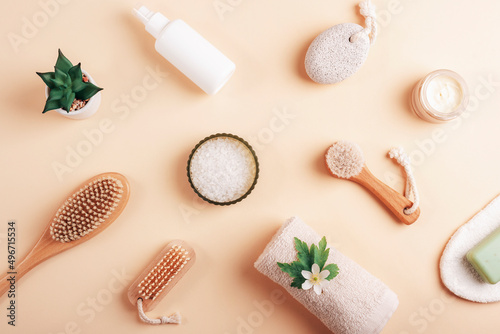 Cosmetic flat lay on neutral beige background. Towel, sea salt, face and body brushes, pumice stone, soap, face cream and body lotion. Spa and wellness concept. Top view