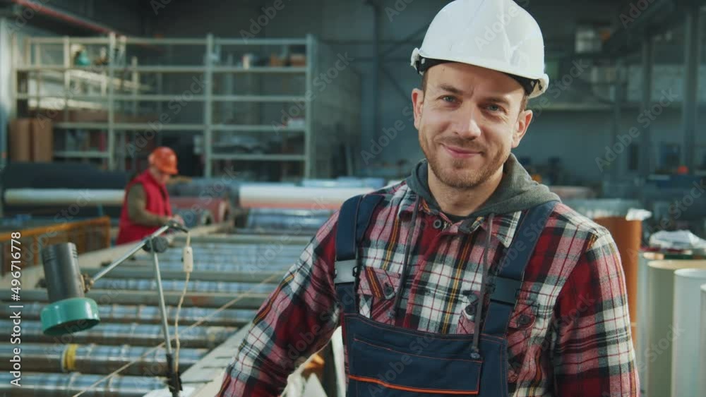 Close up portrait industry engineer man wears safety uniform and hard hat stand look at camera smiling in factory. Inspector in warehouse.