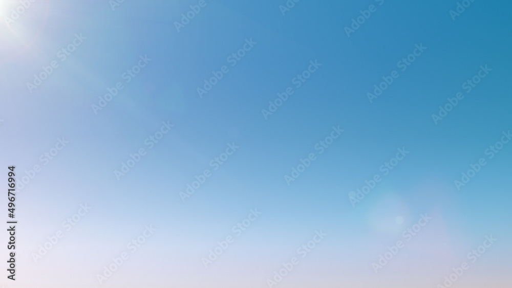 Light blue sky background with sun glare. Clean gradient light blue background. Beautiful light background with space for text. Texture, wallpaper or blank for design