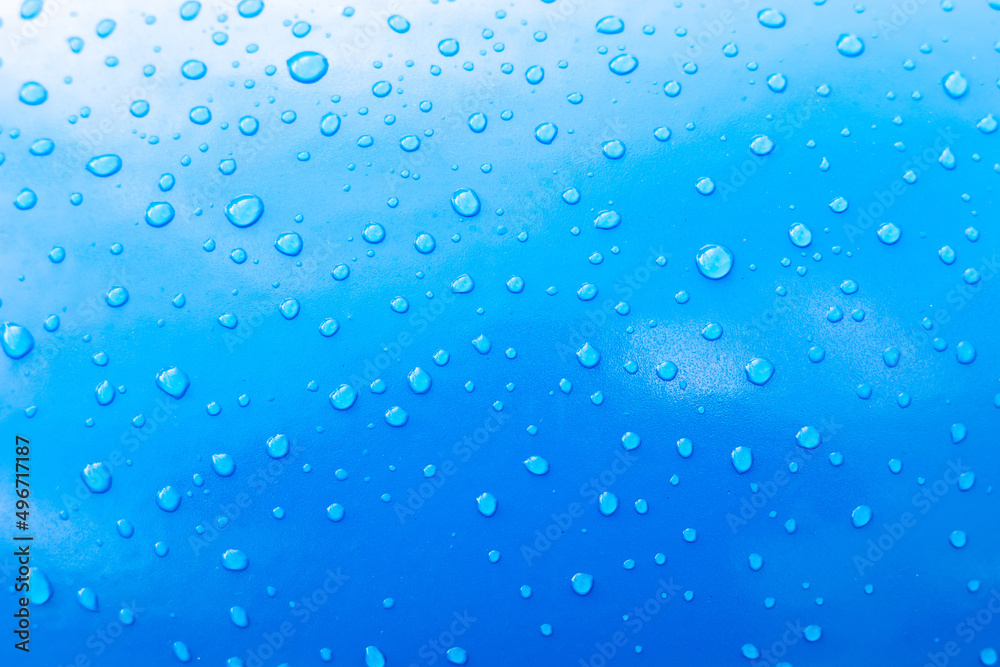 Water drops on blue paint after rain. Blue gradient background or texture. Glare and reflections on water drops. Wallpaper or element for design