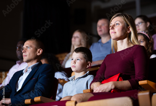 Portrait of family of theatergoers with preteen son watching performance in theater