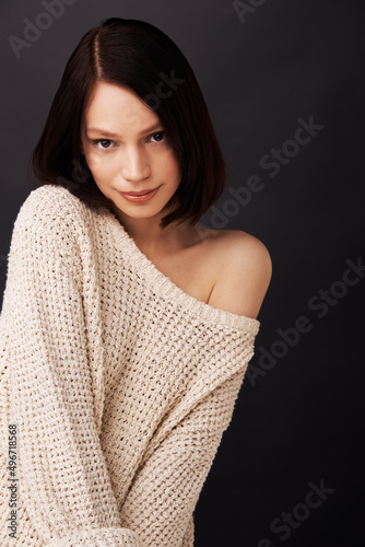 Sweet and shy. Attractive young woman against a dark background.