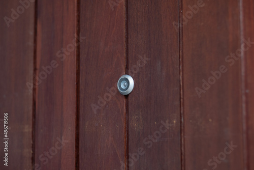 closeup eye door on grey wood background, peephole © waranyu