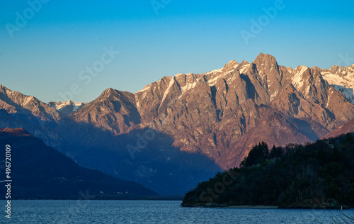 Dramatic sunset scenery of lake Como  set against the foothills of the Alps. Peaks of the mountains covered with snow.