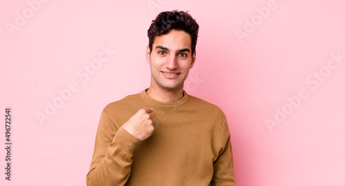 handsome hispanic man looking happy, proud and surprised, cheerfully pointing to self, feeling confident and lofty