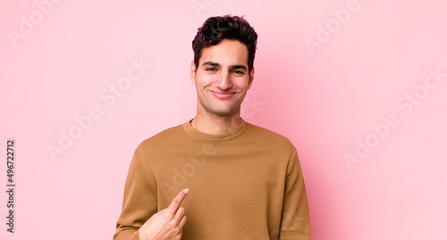 handsome hispanic man looking proud, confident and happy, smiling and pointing to self or making number one sign
