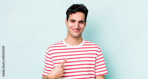handsome hispanic man looking proud, confident and happy, smiling and pointing to self or making number one sign