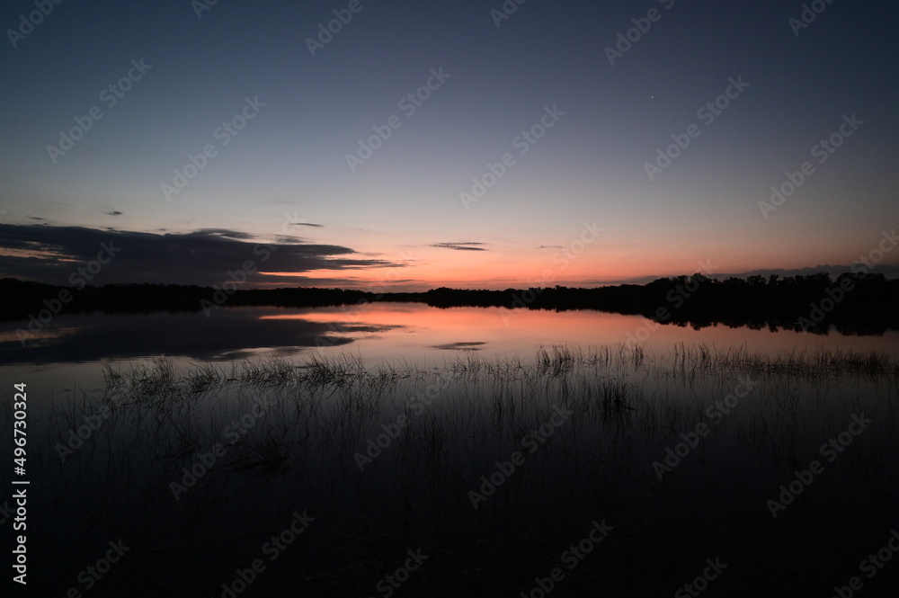 Colorful sunrise reflected in the calm water of Nine Mile Pond in Everglades National Park, Florida.