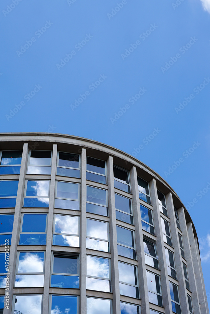 Paris, France - The reflection of a blue sky with clouds in the windows of a curved, reflective, office building.  Image has copy space.