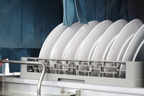 The automatic dishwasher with white clean dishes in basket .For restaurant. photo