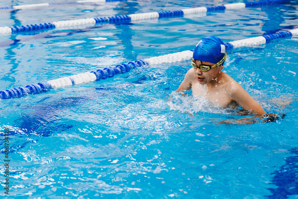 latin child boy swimmer wearing cap and goggles in a swimming training holding On Starting Block In the Pool in Mexico Latin America	