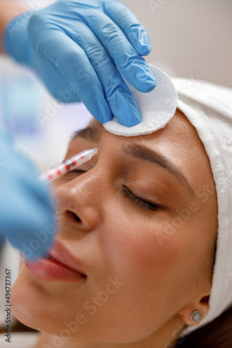 Closeup of female face getting botox injection in forehead to get rid of wrinkles.