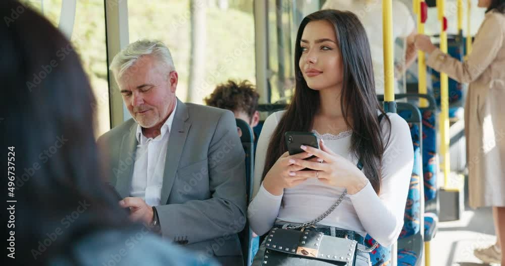 Beautiful brunette girl is holding phone and browsing social media student on way back from university by bus older man
