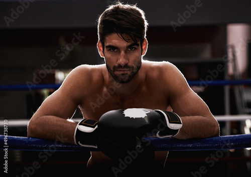 This ring is mone. Portrait of a young boxer leaning on the ropes of a boxing ring.